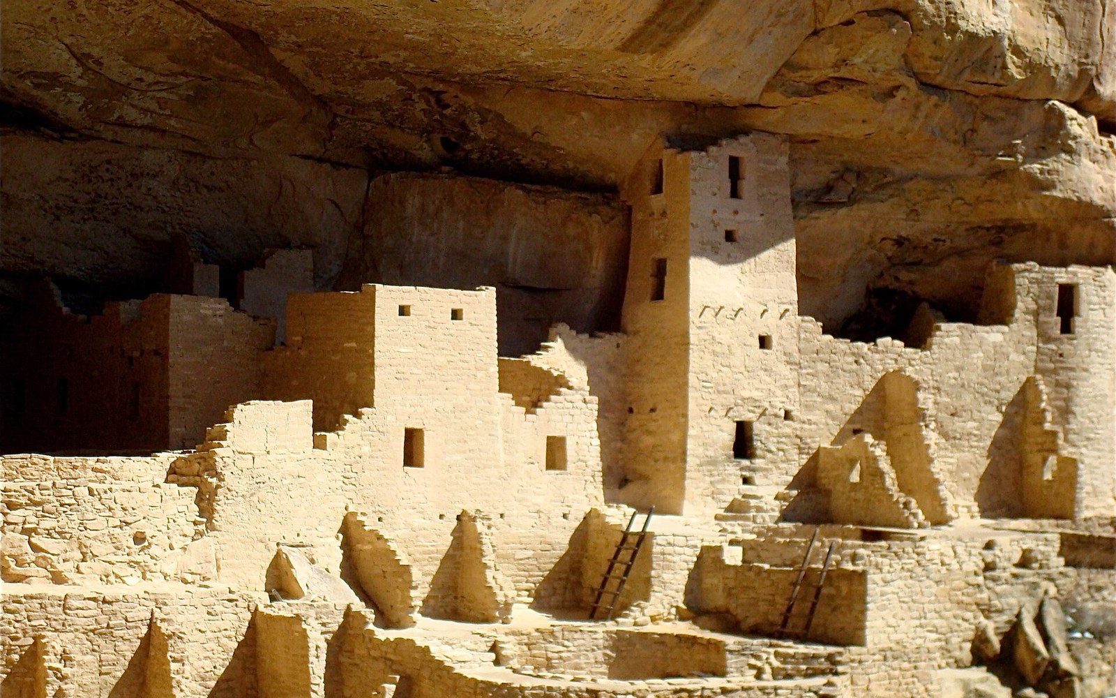 Cliff Palace in late sun. The NPS inventory records roughly 150 rooms and 23 kivas in the single alcove.